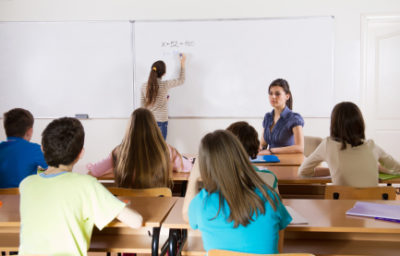 Preteen schoolgirl writing a task on white board.